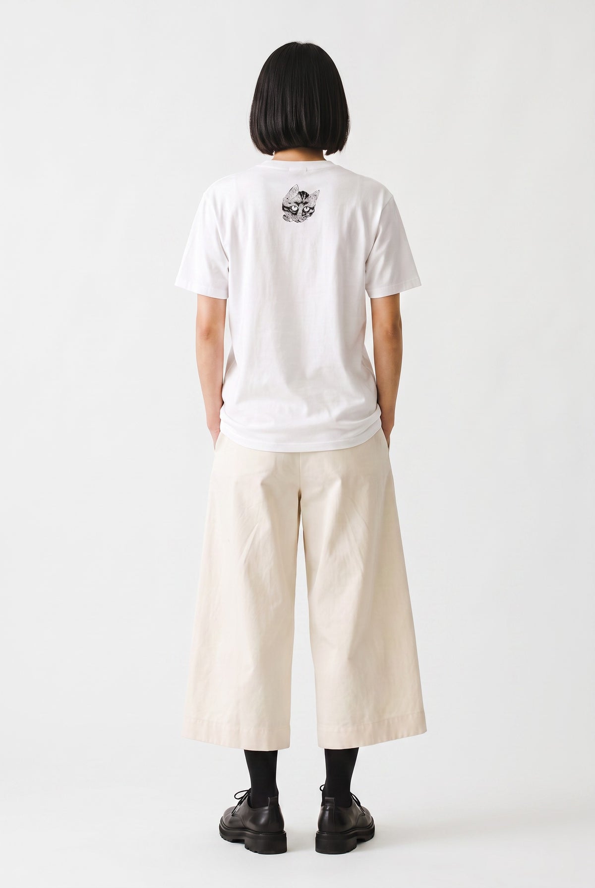 Model wearing a white T-shirt with a small Kawanabe Kyōsai cat illustration printed near the back collar.